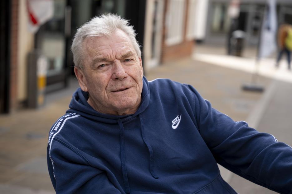 A man in a blue Nike hoodie looks towards the viewer.