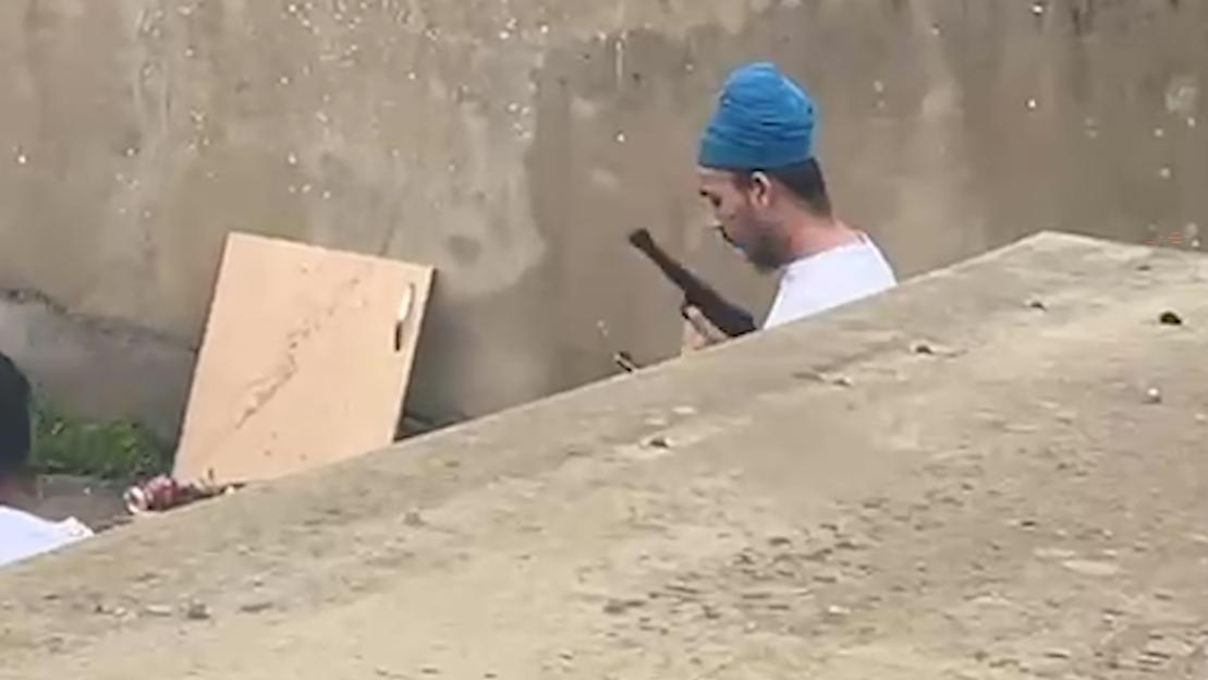 Vickrum Digwa holding a gun in his back garden.