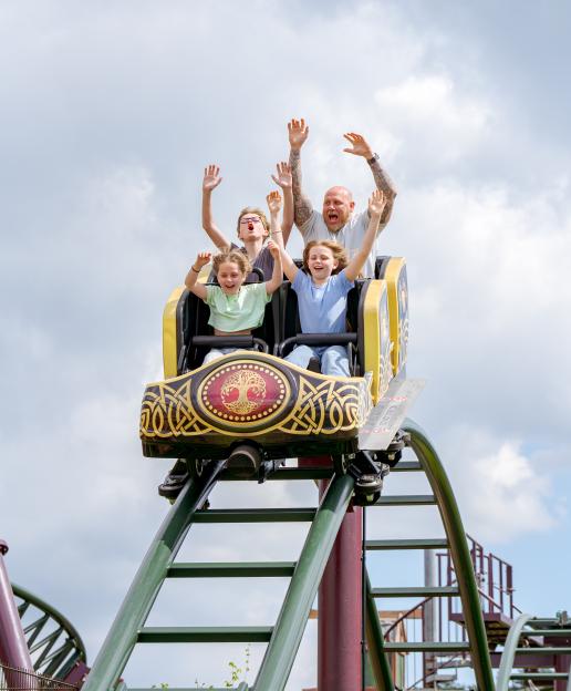 Four people with their hands raised on a rollercoaster.