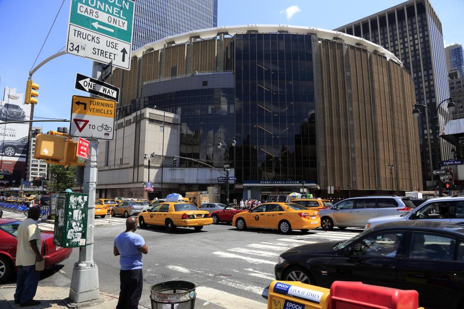 Exterior view of Madison Square Garden with traffic on a city street.