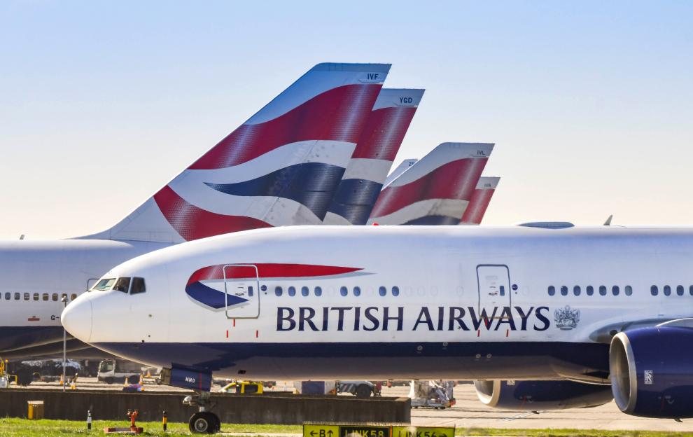 British Airways Boeing 777 taxiing for take-off with other British Airways aircraft tails in the background.