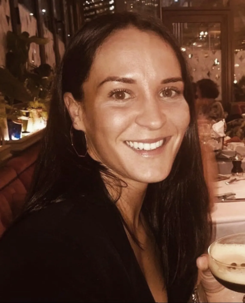 A woman smiling and holding a cocktail.