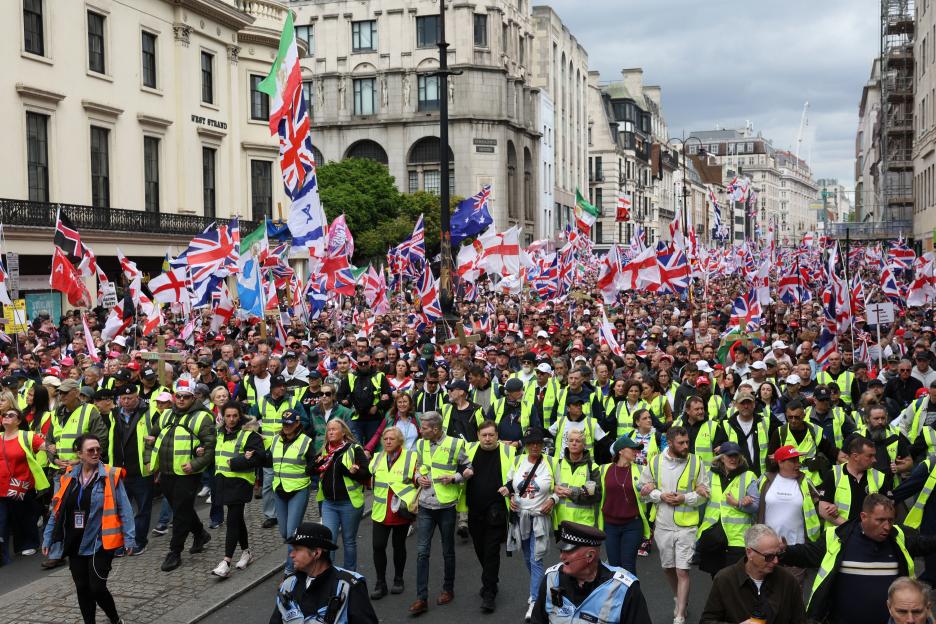 Crowd of Tommy Robinson supporters marching in London with Union Jack flags and other national flags.
