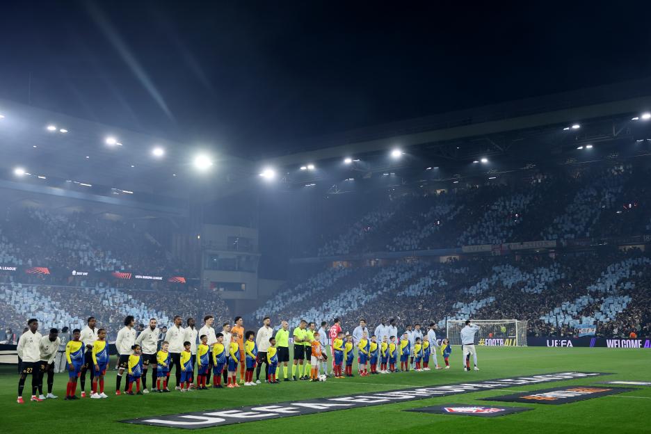 Aston Villa FC and Lille OSC football teams, accompanied by child mascots, line up on the pitch for the UEFA Europa League Round of 16 match.