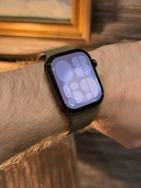 An Apple Watch Series 7 with a green band worn on a wrist.