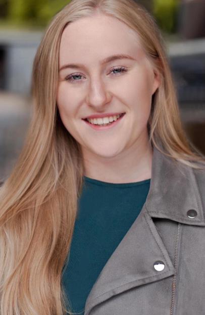 Headshot of a smiling young woman with long blonde hair and a grey jacket.