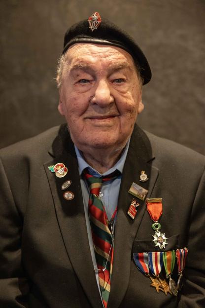Richard Aldred, a 99-year-old World War II veteran, wearing a beret and a suit adorned with military medals and pins.
