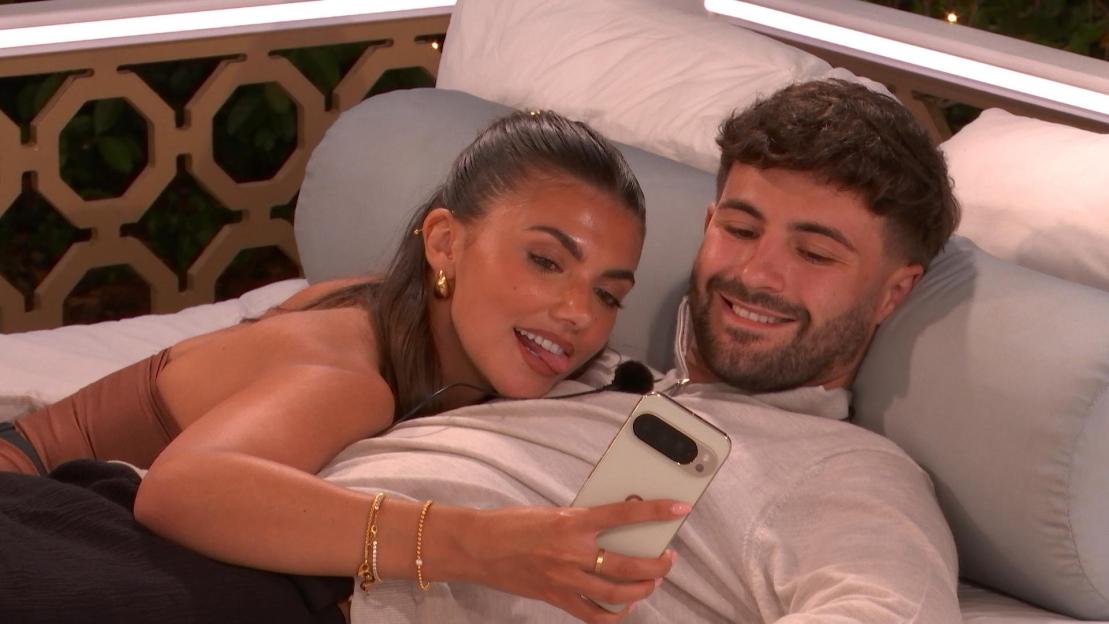 Ciaran Davies and Samie Elishi lying on a bed while looking at a phone.