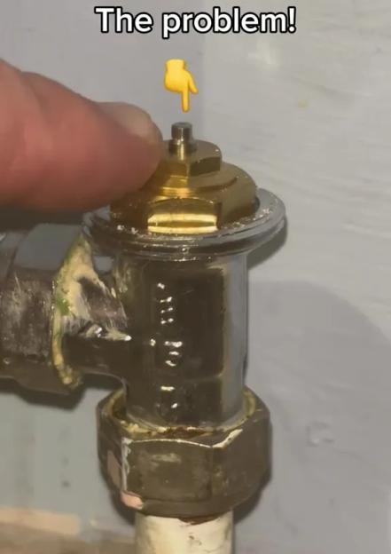 A person's finger touching the pin of a radiator valve.