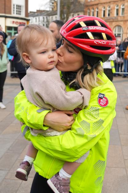 Mollie King, wearing a cycling helmet, kisses her daughter Annabella.