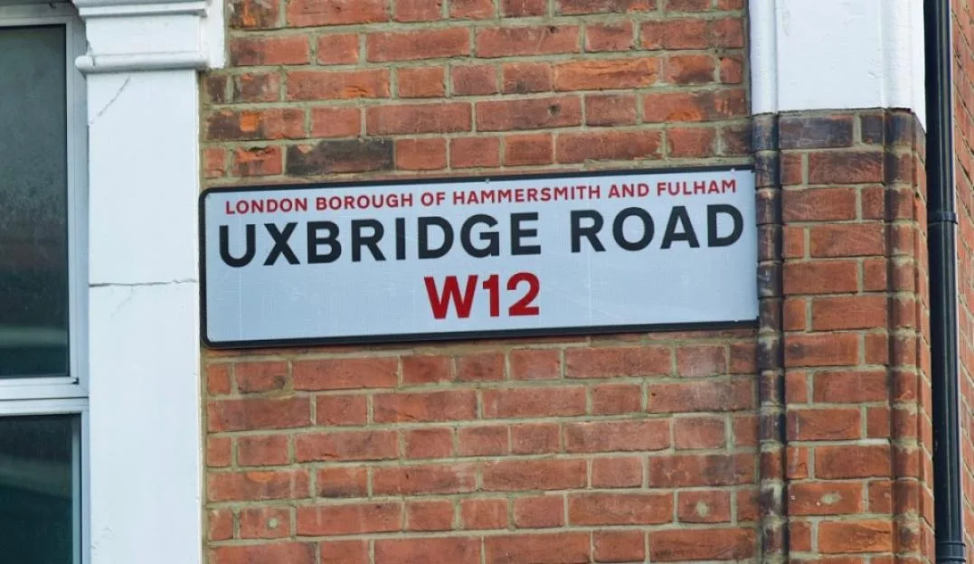 A street sign on a brick wall reading "UXBRIDGE ROAD W12, LONDON BOROUGH OF HAMMERSMITH AND FULHAM".