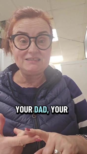 A woman with red hair and glasses wearing a puffer vest, speaking, with the text "YOUR DAD, YOUR" at the bottom of the image.
