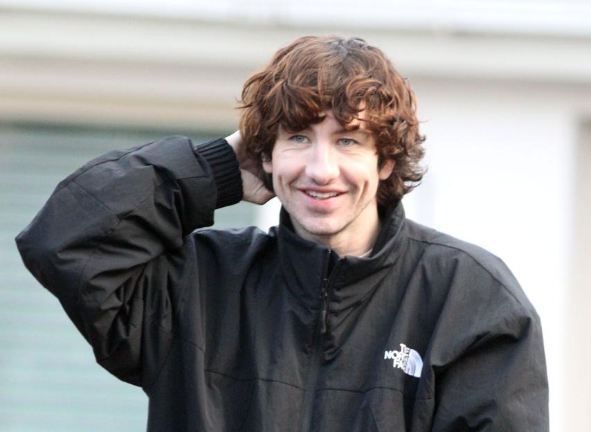 Actor Barry Keoghan on set in Dublin wearing a black jacket and striped pajama bottoms.