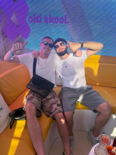 Cole Palmer and another man giving thumbs up, sitting on a yellow couch with a sign that says "old skool" in the background.