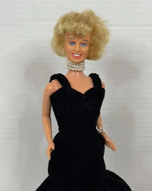 A doll resembling Princess Diana, wearing a black evening gown and pearl choker.