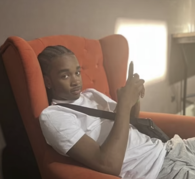 Man sitting in an orange armchair, looking at the camera.