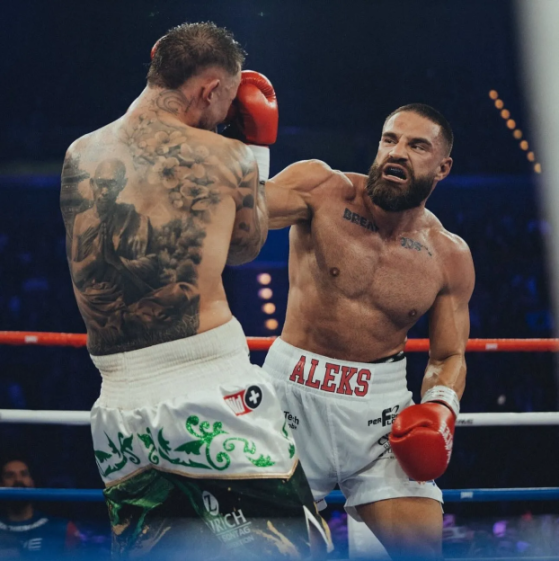 Two boxers, one with a full back tattoo and the other with a beard, in a boxing match.