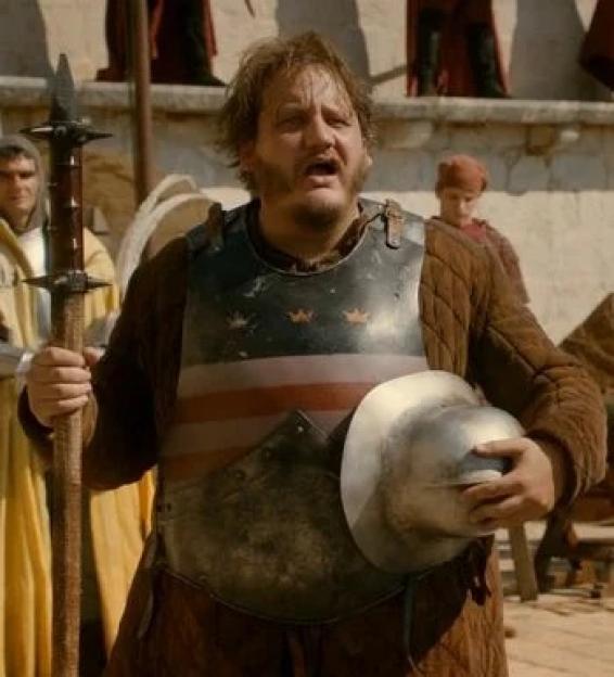 A man in armor, holding a spear and helmet, with a surprised expression.