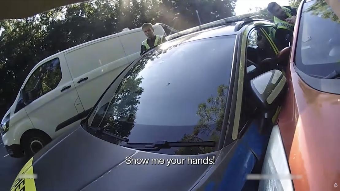 Police officers arresting a suspect in a car.