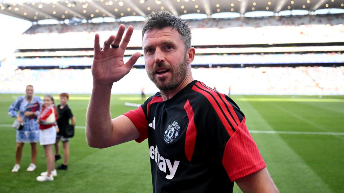 Manchester United coach Michael Carrick waving from a soccer field.