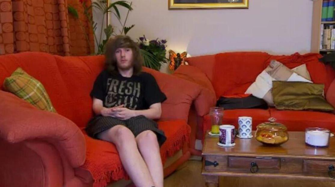 Jay from Gogglebox sitting on a red sofa.