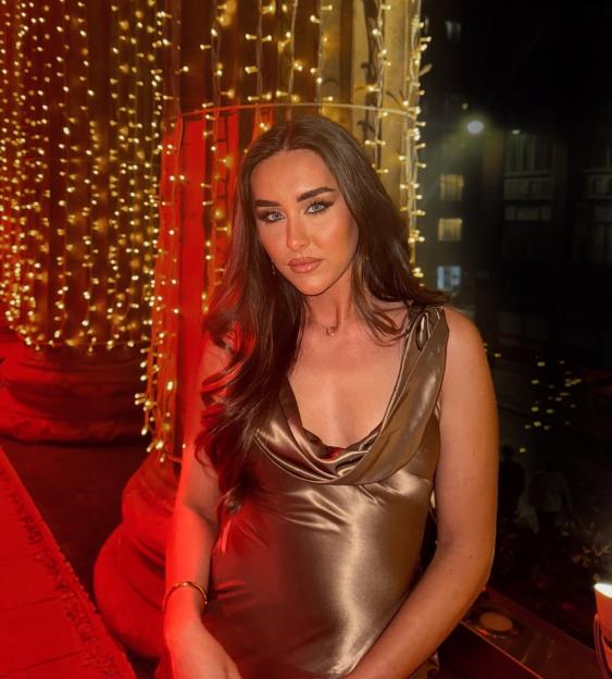 Miya Lind in a shiny brown dress against a background of festive lights.