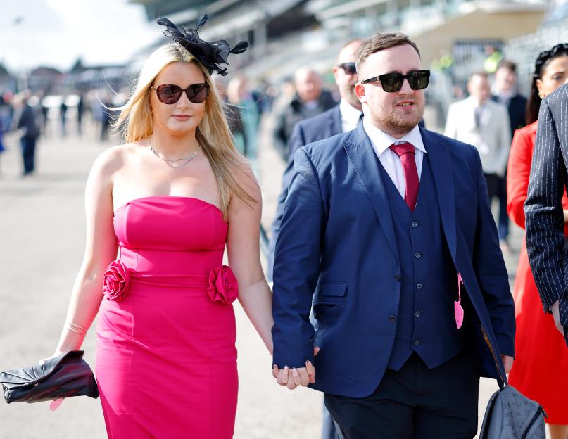 Faith Millar in a pink dress and Luke Littler in a blue suit holding hands at the Cheltenham Festival.