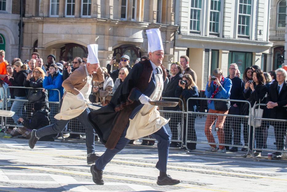 Livery members in chef hats and aprons run during a Pancake Day race in Guildhall, London.