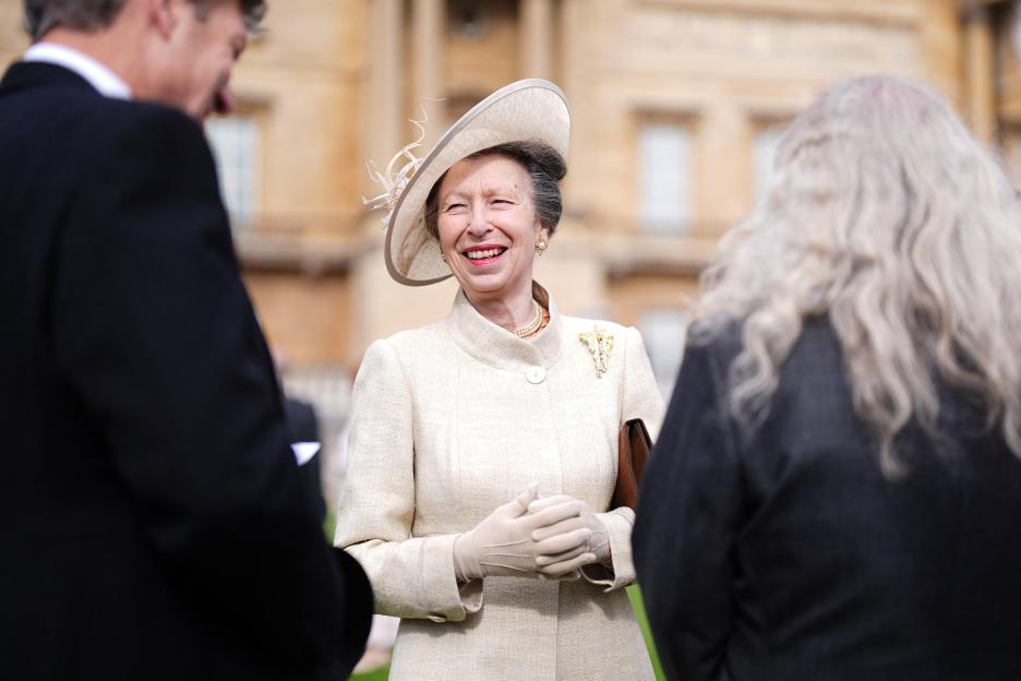 Princess Anne smiling at guests at a garden party at Buckingham Palace.