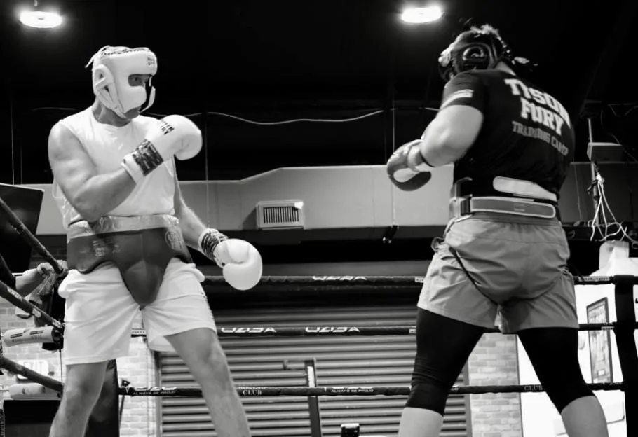 Two boxers sparring in a ring in a black and white image.