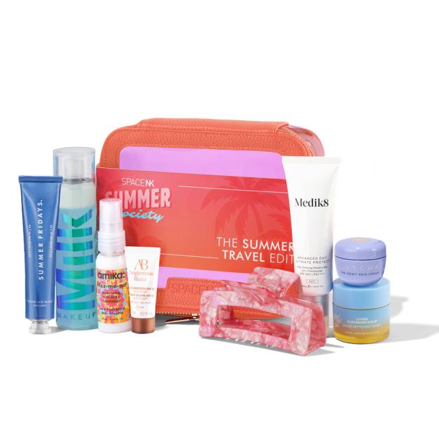 A collection of summer beauty products from Space NK, including a travel bag, moisturizers, sunscreen, and hair products.