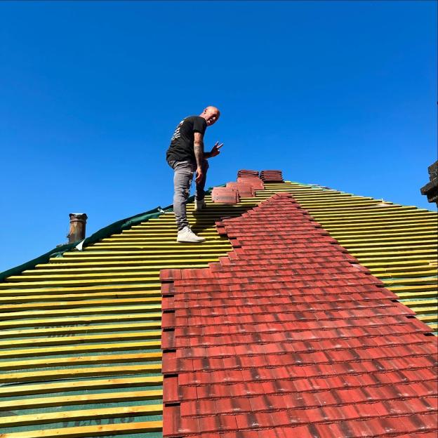 John Hendy from East 17 standing on a partially re-tiled roof.