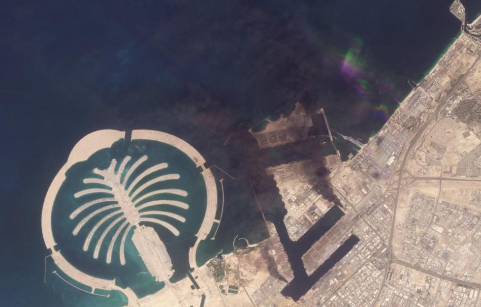 A satellite image of Jebel Ali Port in Dubai, showing the large, palm-shaped artificial island and the sprawling industrial port area.