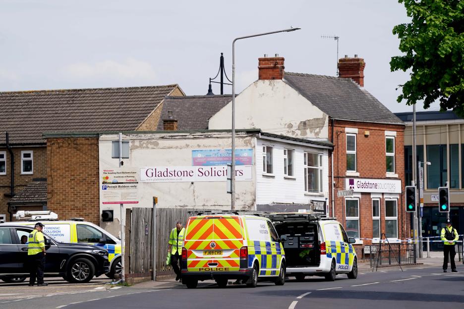 A police officer stands behind police tape blocking a street after pedestrians were struck by a vehicle.