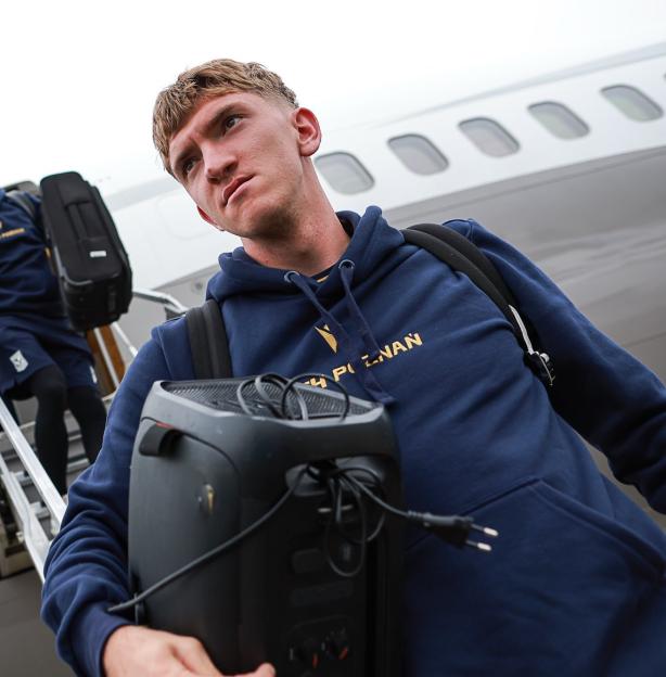 A man wearing a "Lech Poznan" hoodie carries a speaker onto an airplane.
