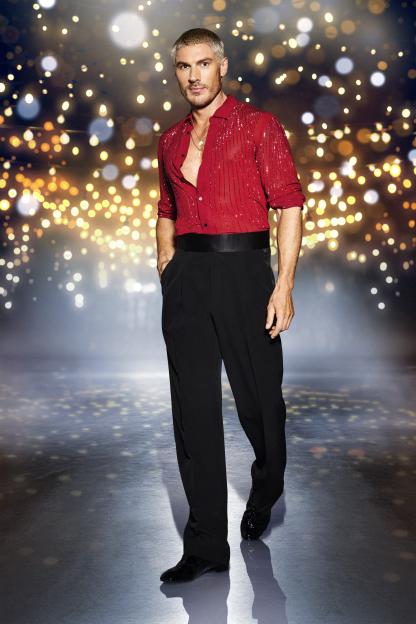 Chris Appleton, a contestant on the dancing show "Strictly Come Dancing," poses in a red sequined shirt and black trousers against a sparkling background.