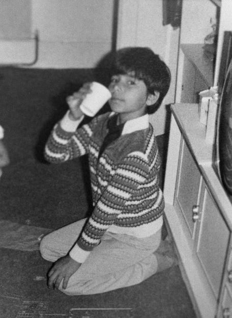 Vishal Mehrotra, an 8-year-old boy, kneeling and drinking from a cup.