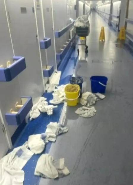 Hospital hallway with wet floor and cleaning supplies.