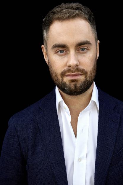 Headshot of Freddie Sheridan wearing a white shirt and navy blazer.