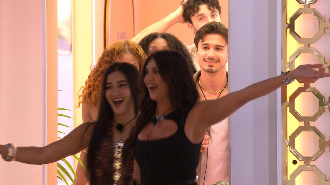 Cast members from Love Island looking excited and smiling.