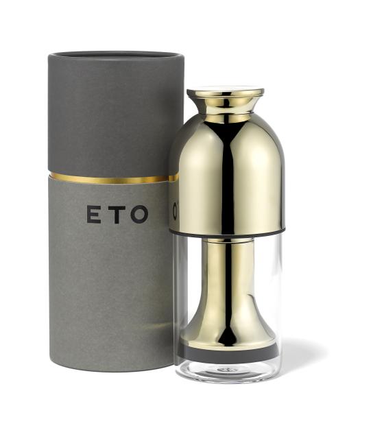 Eto decanter next to its gray and gold cylindrical packaging.