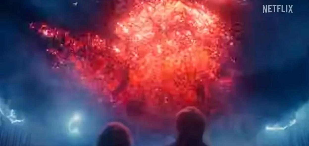 Two people look up at a giant red, glowing, swirling mass with bolts of blue lightning in the Netflix series "Stranger Things."