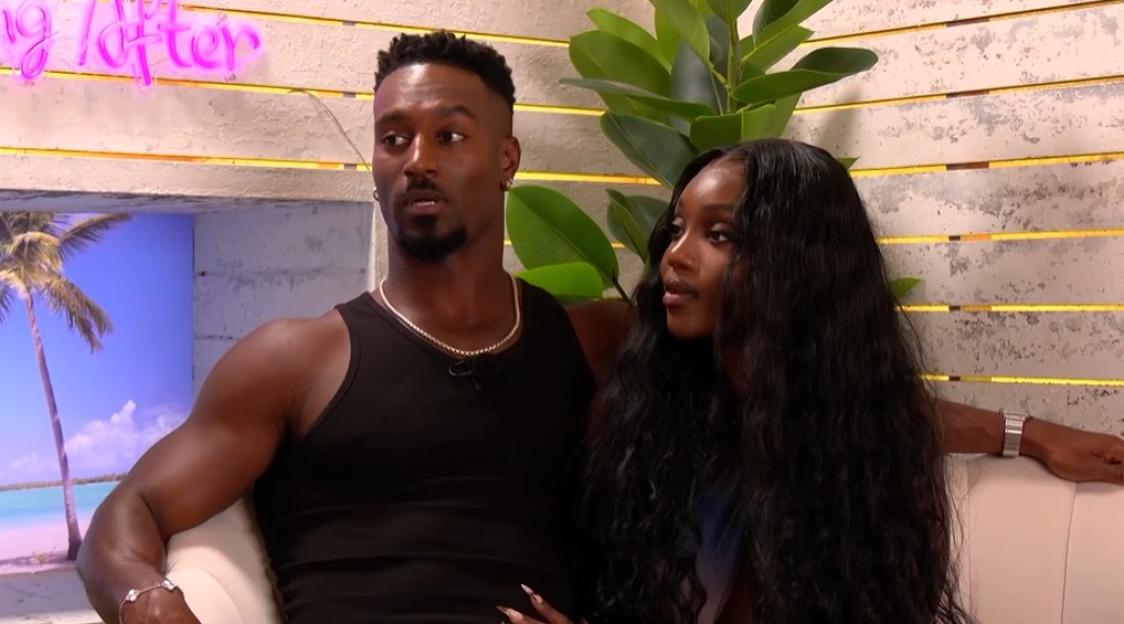 A man and a woman sitting on a couch, the man looking left, the woman looking right.