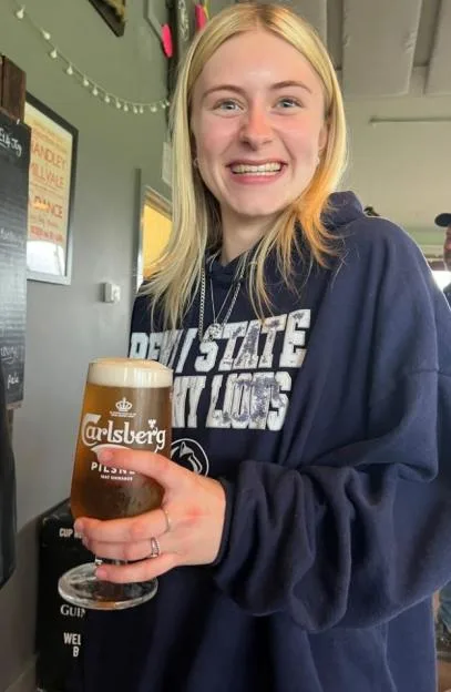 Laionie Kennard smiling while holding a glass of Carlsberg beer.
