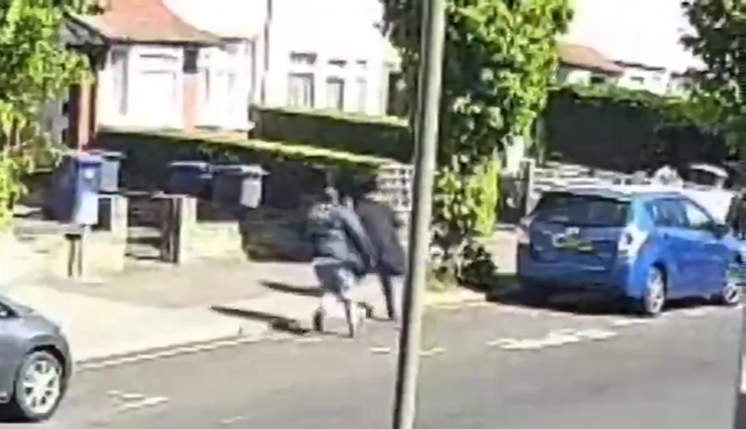 CCTV footage of a residential street with cars, pedestrians, and houses on a sunny day at 11:15 AM.