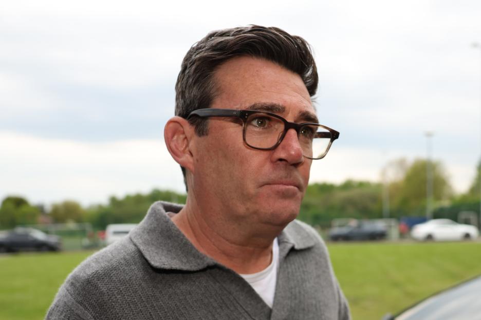 Andy Burnham, Mayor of Greater Manchester, in a grey collared shirt and glasses.