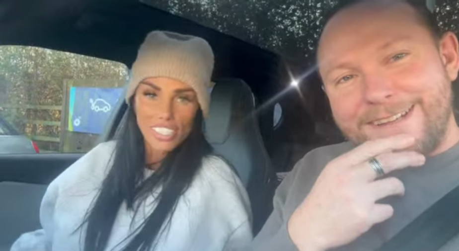 A woman in a knitted hat and a man with a beard smiling in a car.