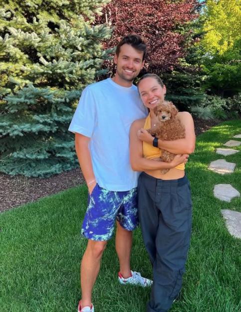 Alexis Warr Burton and Jake Burton posing outdoors with a puppy.