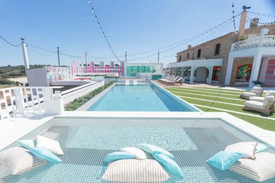 The exterior of the Love Island villa with a large pool, lounge chairs, and a daybed over a second pool.