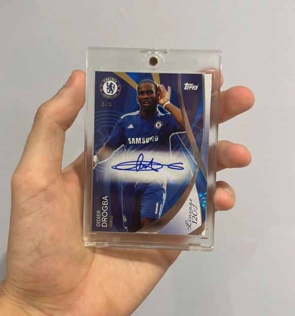 Hand holding a Didier Drogba autographed Chelsea FC football card.